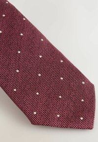 Cravate bordeaux avec un tissage texturé et des pois blancs. Elle présente une extrémité pointue et une finition lisse.