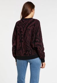 Suéter de gran tamaño en una mezcla de burdeos oscuro y negro, con un patrón texturizado. Puños y dobladillo acanalados, con un corte relajado.
