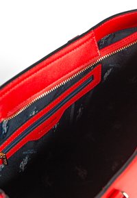 Borsa a mano sintetica rossa con chiusura a zip, caratterizzata da un esterno testurizzato, fodera interna blu navy e numerosi scomparti. Dettagli in zip dorati.