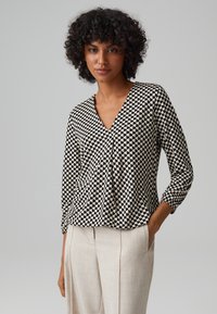 Schwarz-weiße karierte Bluse mit V-Ausschnitt und drei Viertel Ärmeln, mit lockerer Passform und gerafften Details an der Taille.
