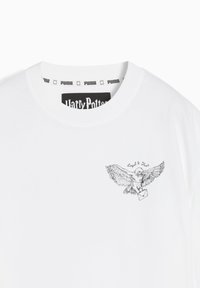 White t-shirt with a round neckline, featuring a black graphic of an owl carrying a letter, and "Loyal & True" text. Puma and Harry Potter branding.