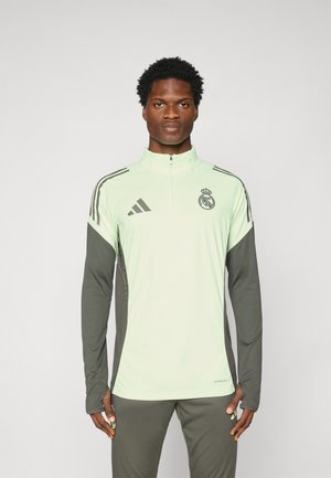 Pullover de sport vert clair avec manches longues, col zippé et accents gris foncé. Présente les logos Adidas et Real Madrid. Tissu doux.