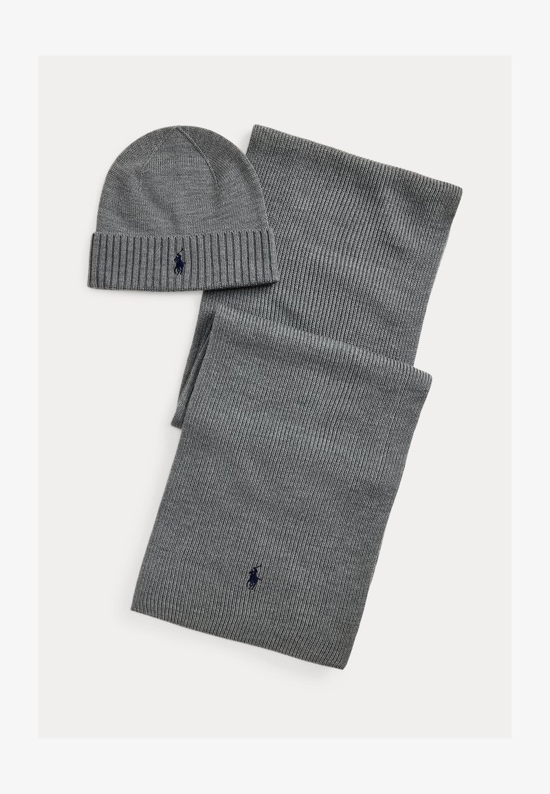 Gray knitted scarf and beanie set. The beanie has a ribbed edge, with a navy logo. Both items feature a textured pattern.