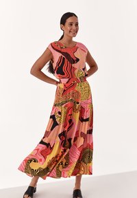 Robe maxi colorée présentant un mélange de motifs abstraits en rose, noir et jaune, avec une coupe décontractée et un design à volants.