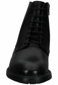 Bota negra de cuero hasta el tobillo con diseño de cordones y cierre de cremallera. Presenta una puntera redondeada y superficie texturizada. Suela gruesa de goma.