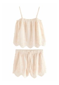 Krämfärgad ärmlös topp och matchande shorts med broderade blommönster och vågiga kanter.