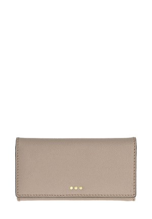 Portefeuille en cuir beige avec une texture lisse et trois clous métalliques à l'avant. Présente des bords cousus et une forme rectangulaire.