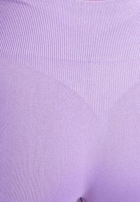 Lavendelgekleurde legging met een geribbelde textuur, voorzien van een driehoekig designelement aan de achterkant, gemaakt van een soepel en rekbaar stof.