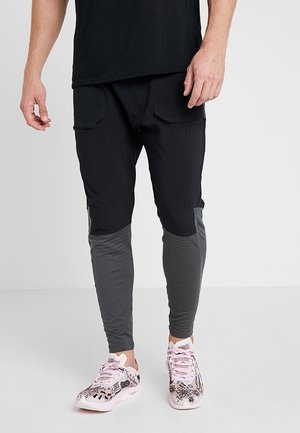 Pantalons de jogging noirs et gris au design ajusté, fabriqués en tissu léger, dotés de poches latérales et d'accents texturés sur les jambes.