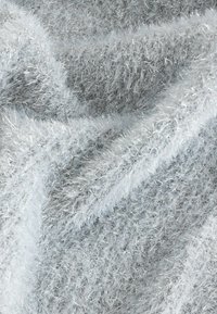 Hõbedase tooni karvane kangas, millel on pehme, tekstureeritud pind ja peened metallilised kiud, mis loovad peegelduva kvaliteedi.