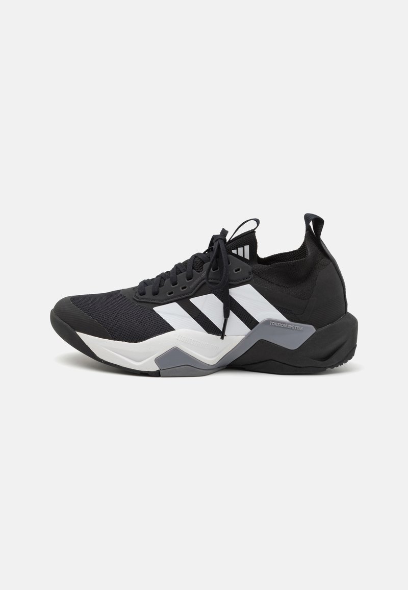 Baskets de sport noires avec une tige texturée, un design à trois bandes blanches et une semelle intermédiaire grise. Présente un col rembourré et un système de laçage.