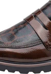 Gros plan sur un mocassin en cuir marron avec un motif peau de serpent et une sangle décorative par-dessus, avec une semelle noire rainurée.