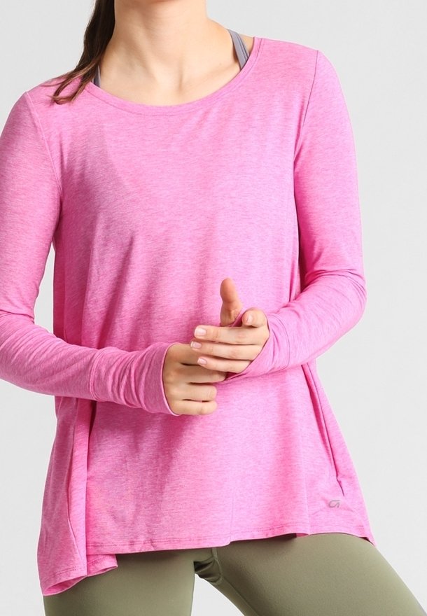 Haut à manches longues en rose clair, fabriqué dans un tissu doux et extensible. Il présente un col rond et des fentes sur les côtés pour un meilleur confort.