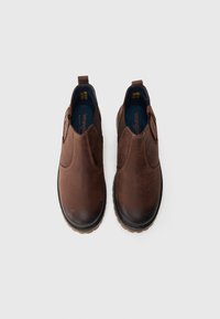 Hnědé kožené slip-on boty s elastickými bočními panely a robustní černou podešví. Mají hladký povrch a pevnou konstrukci.