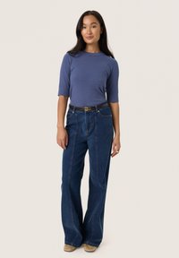 Blue ribbed sweater with three-quarter sleeves, paired with high-waisted, wide-leg dark denim jeans. Brown belt with gold buckle accents.