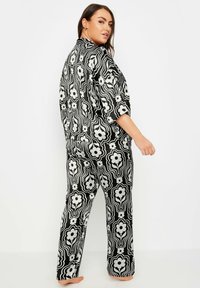 Ett svart och vitt blommönstrat pyjamasset med en lös passform, breda ärmar och matchande raka byxor.