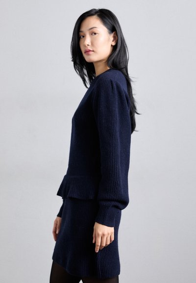 Vestido suéter de punto azul marino con una silueta ajustada, textura acanalada y peplum acampanado en la cintura, con mangas largas y escote redondo.