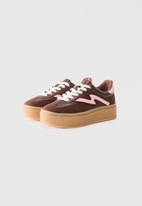 Baskets marron avec un accent rose, dotées d'un design en daim et en cuir, d'une semelle épaisse et de lacets blancs. Style minimaliste et textures contrastées.