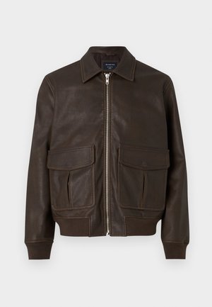 Smeđa kožna bomber jakna s prednim zatvaračem, dvije velike preklopne džepove, rebraste manžete i pojas, prikazana na bijeloj pozadini.