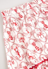 Raudonos ir baltos audinys su omaro ir ananaso raštu, papuoštas dekoratyviniais ovalais ir banguota raudona apdaila liemens juostoje.