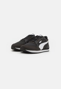 Zapatillas deportivas negras con acentos blancos, con una parte superior texturizada, cierre de cordones y suela acolchada para mayor comodidad y soporte.