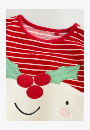 Tessuto a righe rosse e bianche con applicazione di un volto sorridente, foglie di agrifoglio verdi e tre bacche rosse su abbigliamento festivo.