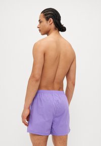 Ανδρικά μωβ μαγιό φτιαγμένα από ελαφρύ ύφασμα, με ελαστική μέση και χαλαρή εφαρμογή. Λείο υλικό, μήκος μέχρι το μέσο του  μηρού.