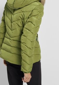 Grønne puffjakke med et chevronmønster, der har hætte og ribbede manchetter, designet med en glat overflade og sidelomme med lynlås.