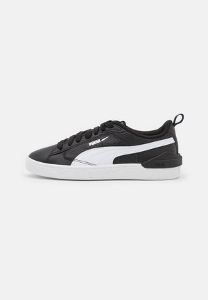 Czarny niski sneaker Puma z białym paskiem po boku, białą podeszwą, czarnymi sznurówkami i pętelką na pięcie, pokazany z widoku od wewnętrznej strony.