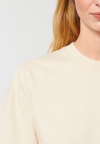 Beige bomulds sweatshirts med rund hals og korte ærmer, der har en blød tekstur og subtile farvede pletter.