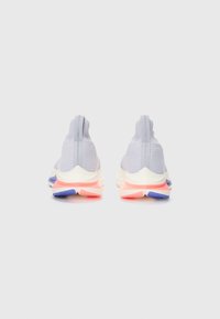 Baskets de sport gris clair avec une tige en tricot texturé, des accents réfléchissants, et une semelle multicolore dans des teintes de rose, bleu et blanc.