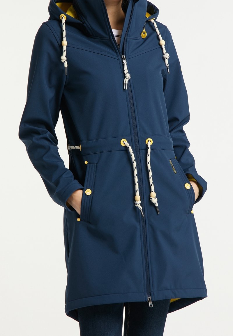 Námornická modrá nepromokavá bunda s kapucí, žlutou podšívkou a ozdobnými uzly. Obsahuje přední kapsy a stahovací pás. Hladká textura.
