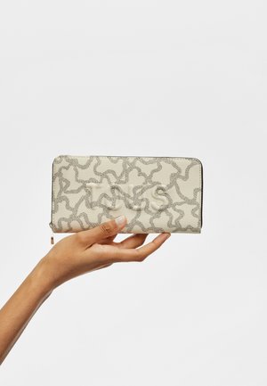 Portefeuille beige avec un motif texturé de lignes ondulées dans des tons plus sombres, doté d'une fermeture éclair et d'un détail de logo embossé sur l'avant.