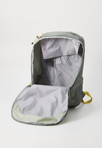 Šedý batoh se zipovým otvorem, obsahující světle šedý interiér, žluté akcenty a prostornou hlavní komoru.