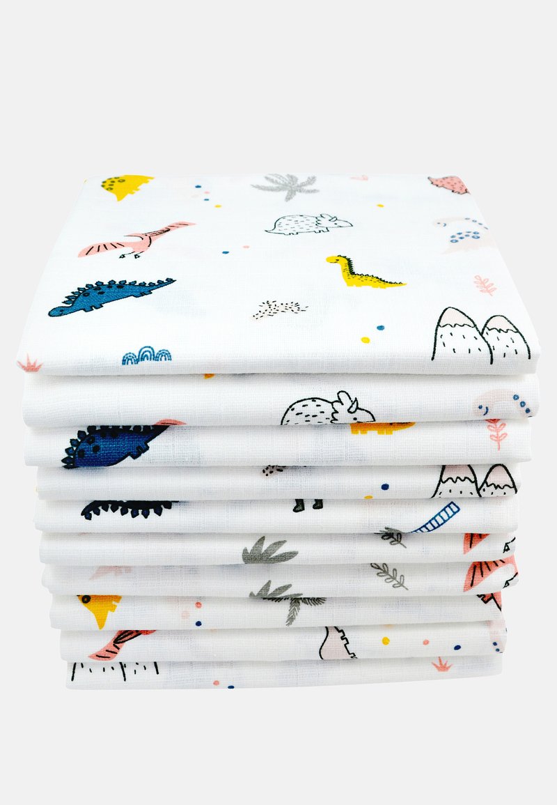 Pile de tissu en coton présentant des motifs colorés d'animaux et de montagnes sur un fond blanc, avec différents motifs et textures visibles.