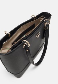 Musta strukturoidu käsilaukku, joka on valmistettu tekstuurimateriaalista, kultaisilla yksityiskohdilla, kaksilla kahvoilla ja vetoketjulla suljettavalla osastolla, jossa on beige sisustus.