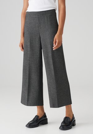 Wijdvallende broek in donkergrijze houndstoothpatroon, met een gladde tailleband en subtiele textuur, gecombineerd met zwarte instappers.