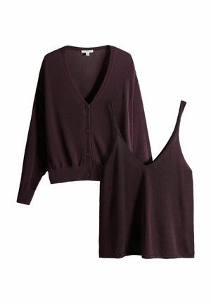 Dunkellila gestrickter Cardigan mit Knöpfen kombiniert mit passendem ärmellosem V-Ausschnitt-Top auf weißem Hintergrund.