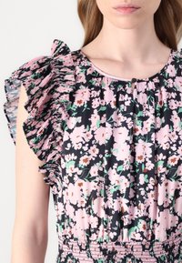 Kukallinen mekko, jossa on vaaleanpunaisia ja vihreitä kukkia tummalla taustalla, rypytetyt hihat ja kuminauhakorsetti; napitus yksityiskohtana kaula-aukossa.