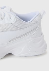 Witte sport sneaker met bovenkant van mesh stof, dikke gevoerde zool, vetersluiting en een trekhaak op de hiel.