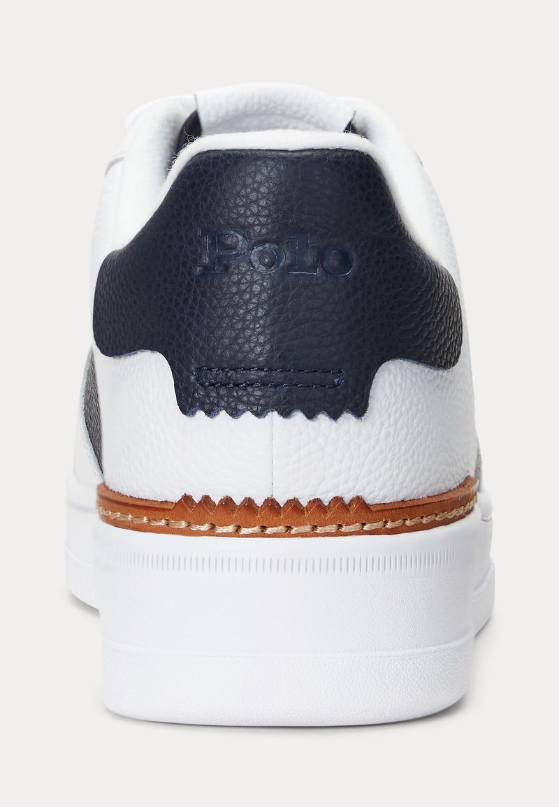 Sneaker bianco con retro navy textured, dettagli in pelle e suola intermedia marrone. Presenta logo embossato sul tallone e bordatura cucita.