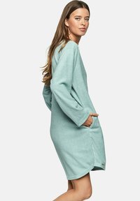 Lichtgroene, lange mouw jurk van zachte, gestructureerde stof met zijzakken en een afgeronde zoom voor een ontspannen pasvorm.