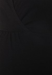 Top ajustado preto com uma textura de algodão suave, apresentando um detalhe de costura franzida e um design de sobreposição na área do busto.