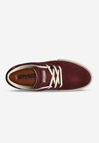 Zapatilla de ante burdeos con cordones blancos, caja de puntera perforada y plantilla con marca. Suela de goma plana con borde marrón claro y detalle de logo.