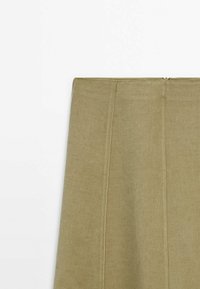 Jupe kaki à texture lisse et légère brillance, dotée d'une fermeture éclair latérale et de coutures verticales pour une coupe ajustée.