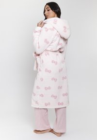 Mysig rosa fleecebadrock med huva, prydd med ett mönster av små rosetter. Matchas med ljusrosa texturerade pyjamasbyxor. Mjuk och varm design.