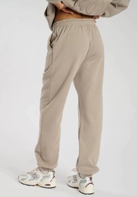 Beige løstsiddende sweatpants med elastisk talje, sidelommer og tapered manchetter. Blødt stof med en glat tekstur.