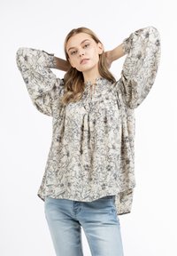 Bluse mit Blumenmuster in Creme mit lockeren Puffärmeln, gerafftem Ausschnitt und Bändern. Leichter Stoff mit einer weichen, strukturierten Oberfläche.
