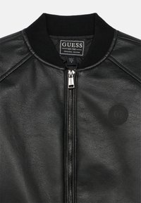 Μαύρο δερμάτινο μπουφάν τύπου bomber με φερμουάρ στο μπροστινό μέρος, ριμπ κολάρο και στρογγυλό έμβλημα. Διαθέτει υφή υλικού και διακριτικές ραφές.