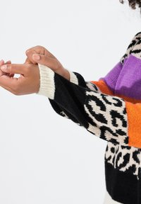 Mehrfarbiger gestrickter Pullover mit Leoparden- und Blockmustern in Schwarz, Orange, Lila und Creme, mit einem gerippten Handgelenkabschluß.